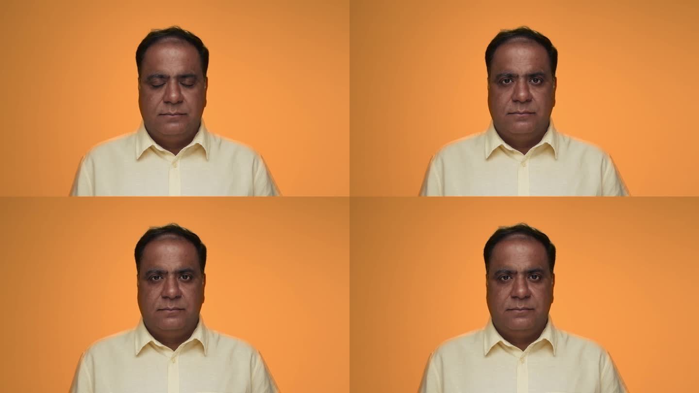 成年印度男子的肖像看着相机在彩色工作室拍摄。在橙色的背景特写上，印度的老男性被孤立。少数民族老年人以