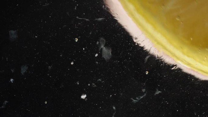 一片柠檬片与蜂蜜一起在玻璃上滑动，并与柠檬汁溶解在一起，黑色背景下的微距镜头。
