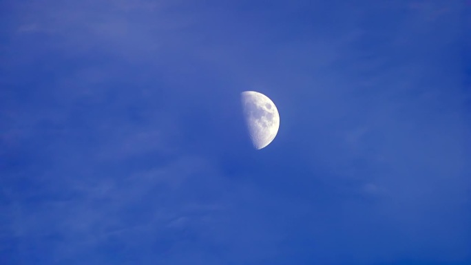 半月形在蓝天上飘过，有一些云，半月形在黄昏。