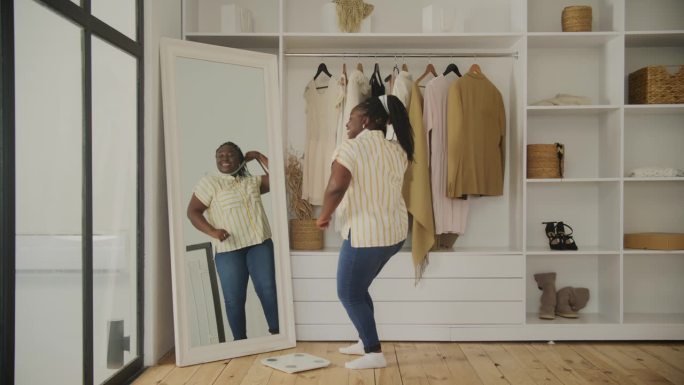 黑人女性为减肥而兴奋。快乐的非洲超重女性在家里跳舞。20多岁的女人想减肥。