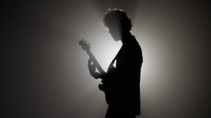 摇滚音乐家在聚光灯下弹吉他的剪影