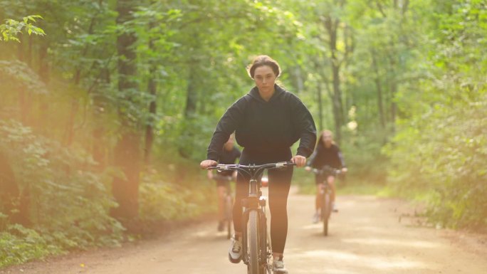 暑假快乐，三个十几岁的女孩或大学生在夏天骑自行车在森林里