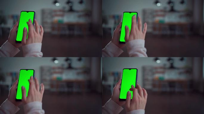 女性的手在家里使用或点击绿色屏幕的智能手机的特写