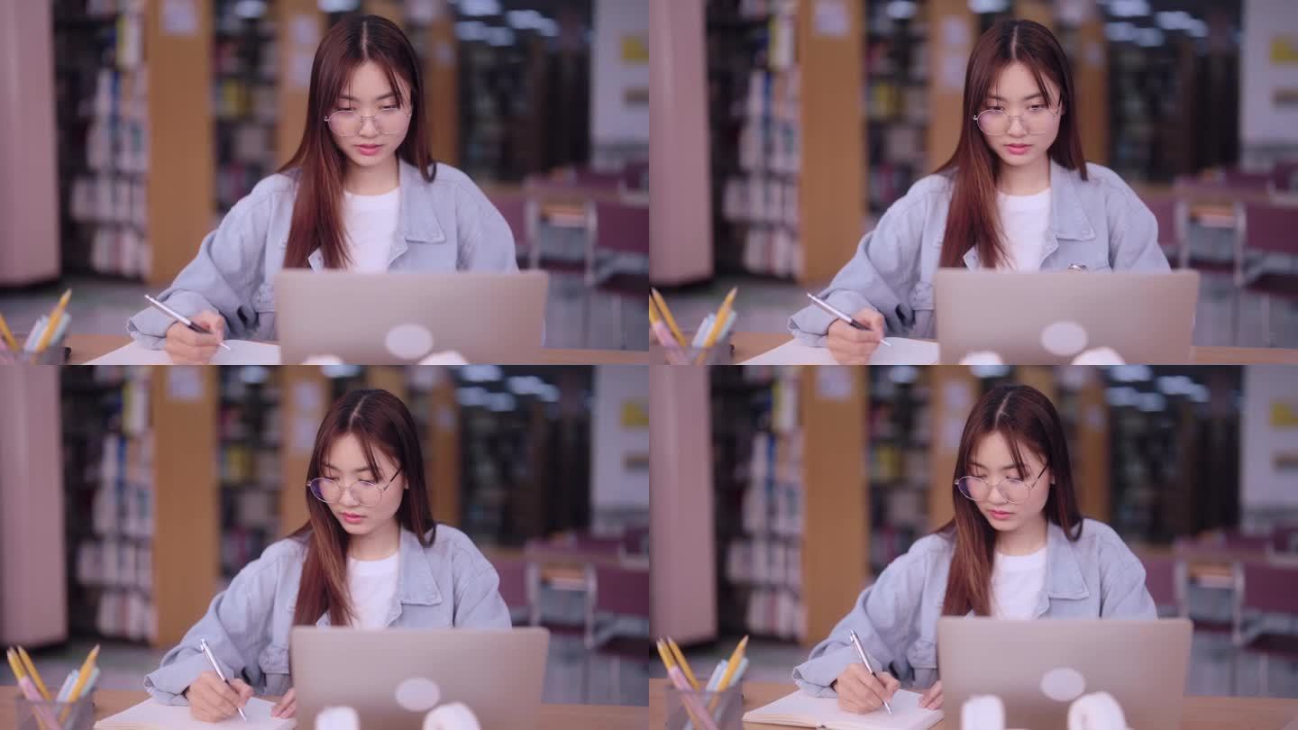一名专注的亚洲女学生在大学图书馆用笔记本电脑记录从互联网上获取的信息。展示有效利用网上资源的学术目的