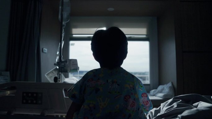 一个患感冒的孩子的后视图，他很无聊，在医院过周末。望着窗外