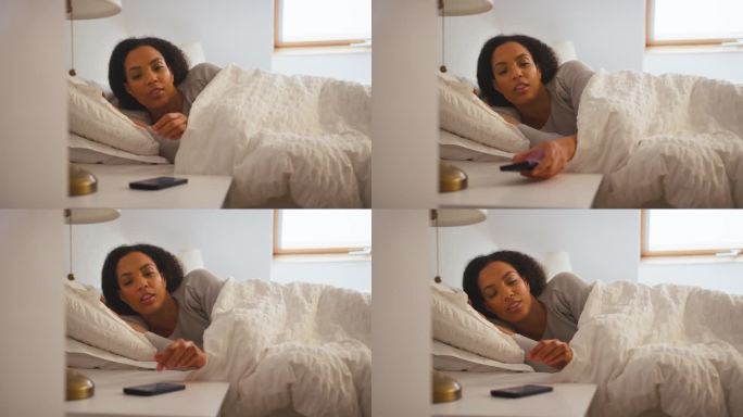 在家躺在床上的女人把手机闹钟关掉了