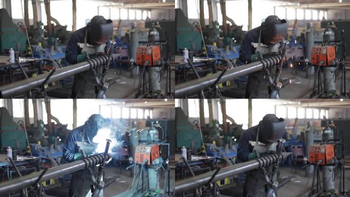 在冶金工厂，穿着蓝色工作服，戴着防护面具的男工人通过电焊连接金属元件。重工业工人在室内用角磨机切割钢