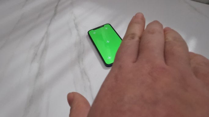 手去拿绿屏手机 拿起手机