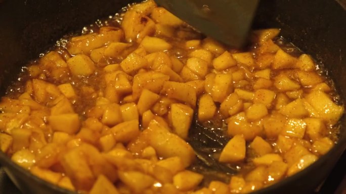 用煎锅煮苹果。蜂蜜糖炸苹果，落配菜。上釉肉桂苹果油锅。焦糖。自制的秋季甜点。脆饼、酸饼、脆饼或派的配