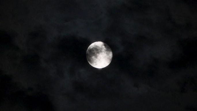 一轮明月挂在天上，有云彩从月亮表面飘过