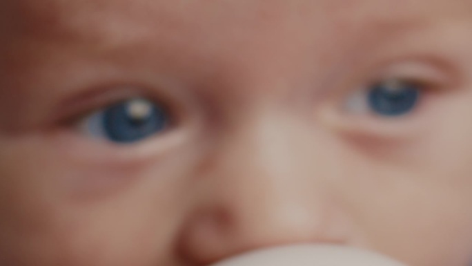 可爱的蓝眼睛小男孩在喝牛奶时看向别处的特写