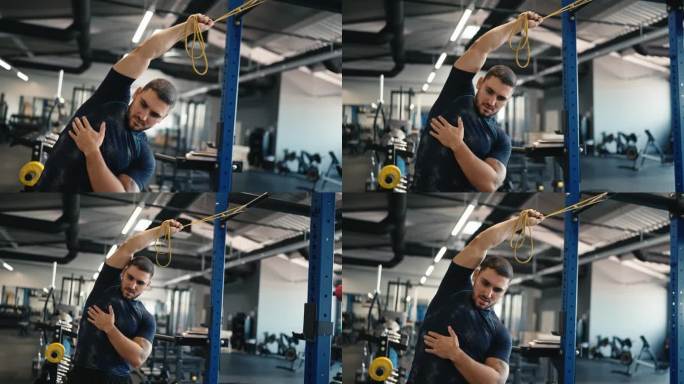 身穿运动服的肌肉男运动员在健身房用健身橡皮筋做伸展运动