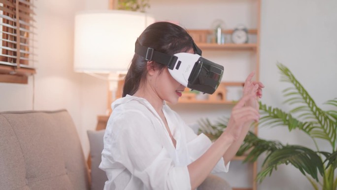 幸福的亚洲妇女画像，戴着虚拟现实眼镜，在家中移动双手