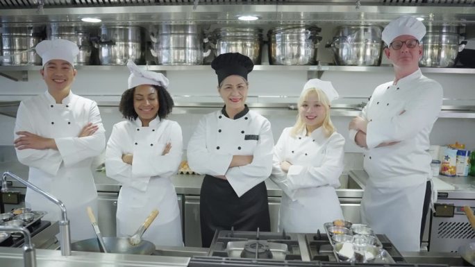 专业的五位厨师代表他们的酒店餐厅团队，厨师同事在镜头前交叉手臂微笑以支持员工敬业和团队合作，多种族厨