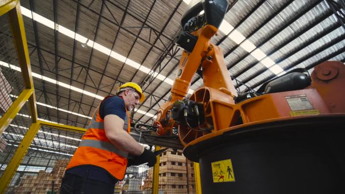 机器人工程师检查和修理自动机械臂的工作，检查情况是否完美，可以在工厂使用。