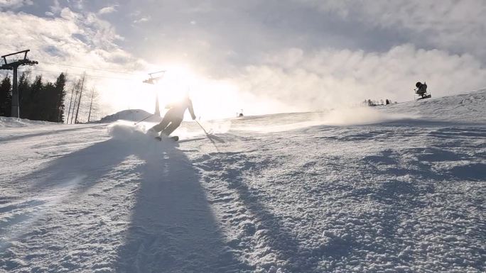 镜头光晕，慢动作:微笑的女人正在滑雪，并向镜头喷洒雪