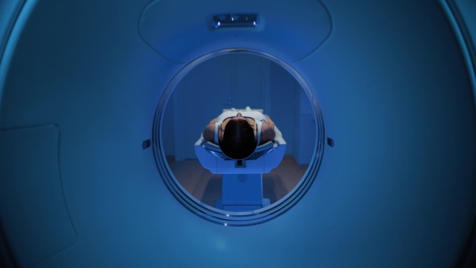在医学实验室，一个匿名的女性病人躺在CT或MRI扫描床上的镜头进行扫描程序。检查开始时，床向相机移动