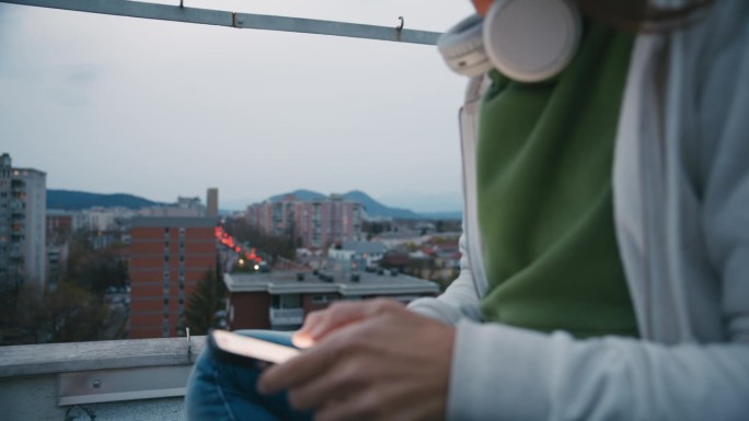 戴耳机的女子在城市屋顶上使用智能手机