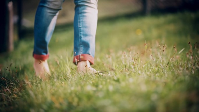 特写:赤脚女人走在阳光明媚的草地上