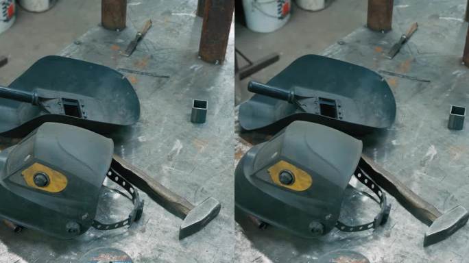 在照明工厂的工作台上焊接头盔和靠近金属件的工具-垂直