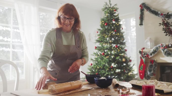 老妇人在家里准备面团做圣诞姜饼的慢动作肖像。快乐的家庭主妇和祖母制作糕点，与家人和朋友分享节日