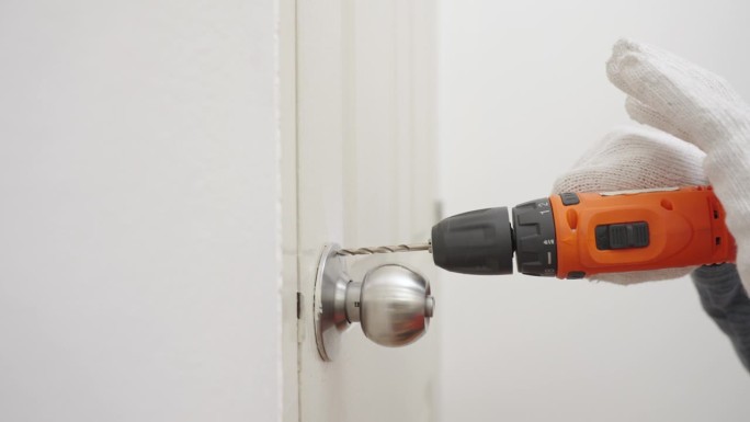 近距离使用无绳电钻的人的手
修理门把手。