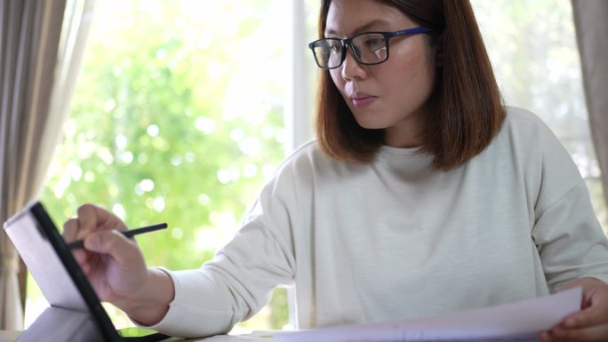 在家里用平板电脑分析财务文件的女性