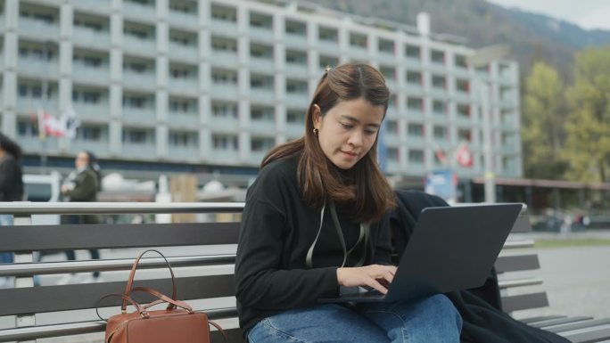 在度假时，坐在城市街道旁，用笔记本电脑上网交流。