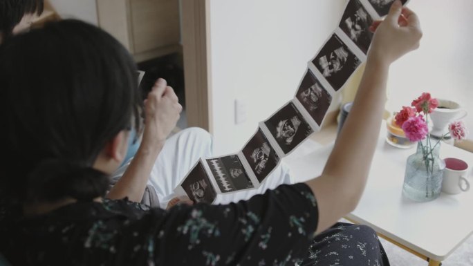 一对年轻的日本夫妇正在检查超声波照片
