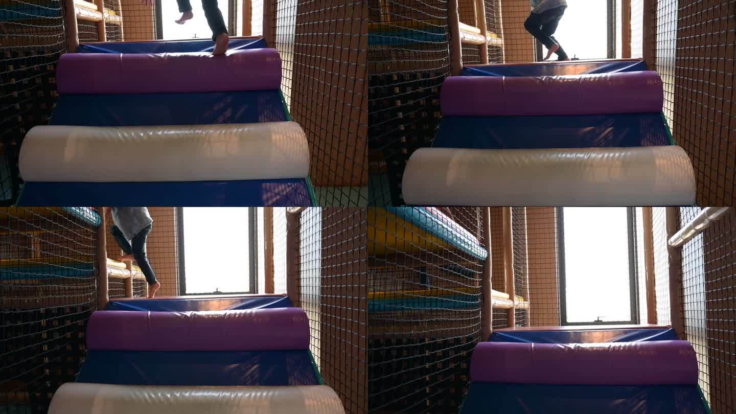 一个男孩在酒店的操场上玩耍，他在彩色垫子上爬，慢动作的场景