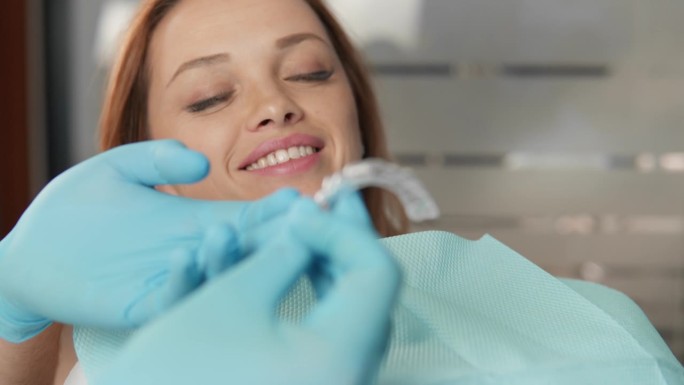 牙医示范牙齿矫正器的工作及矫正器对口腔状况的影响。病人在牙科诊所研究牙齿矫正器治疗的可能性和好处。