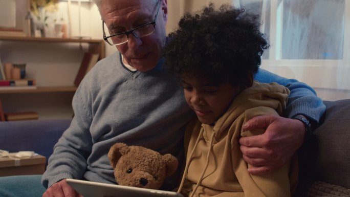 爷爷和孙子在平板电脑上看电影