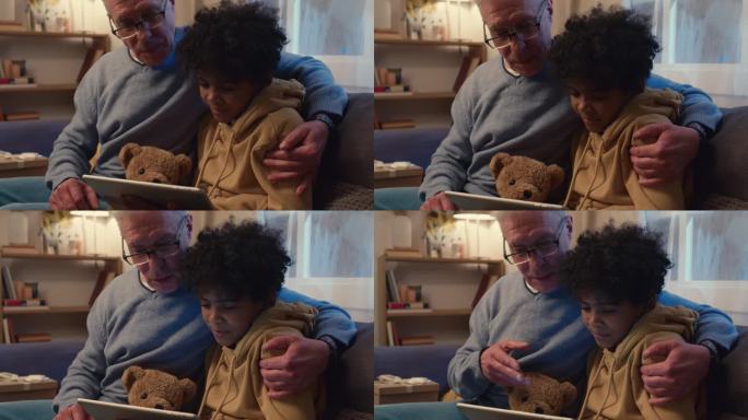 爷爷和孙子在平板电脑上看电影