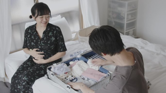 一对年轻的日本夫妇正在收拾婴儿衣服和医院的必需品