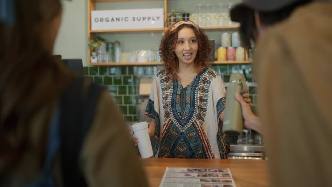 在一家有机食品商店，一位年轻的亚洲顾客选了一份菜单，递给店员一杯。