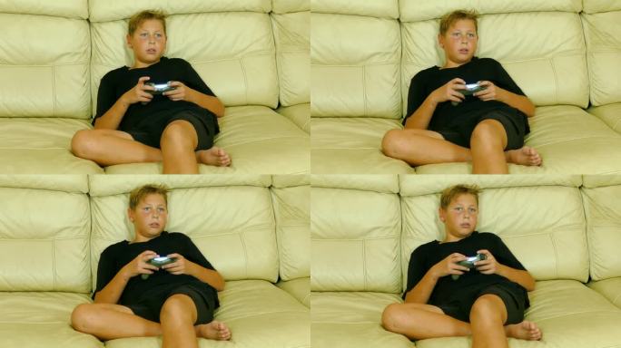 男孩拿着游戏手柄坐在沙发上玩电子游戏