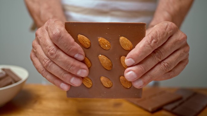 一个老人的手把巧克力掰成两半