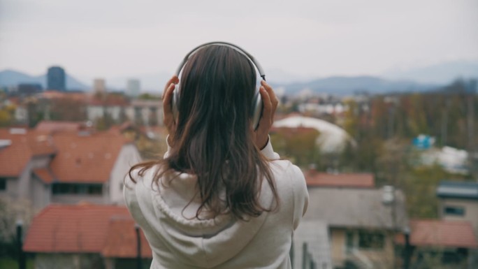 一个女人戴上耳机，眺望城市美景