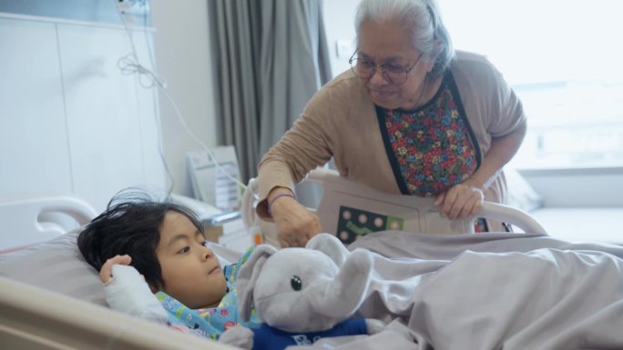 生病的小孩躺在医院的病床上，他的祖母总是在他身边照顾他。