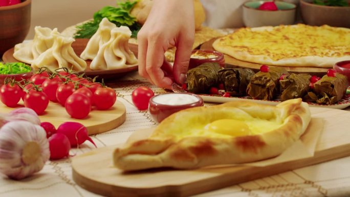 木质餐桌上的格鲁吉亚美食特写。格鲁吉亚菜。阿贾利安·哈恰普里，khinkali, dolma