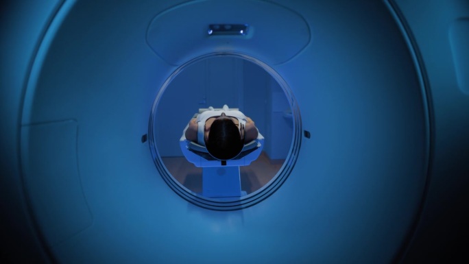 床向相机移动:在拥有高科技设备的医学实验室中，躺在CT或MRI扫描床上的匿名女性患者在专业监督下接受
