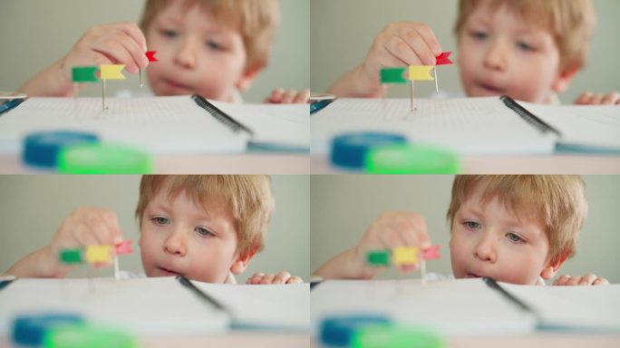 蹒跚学步的男孩用小红标签替换笔记本上的别针