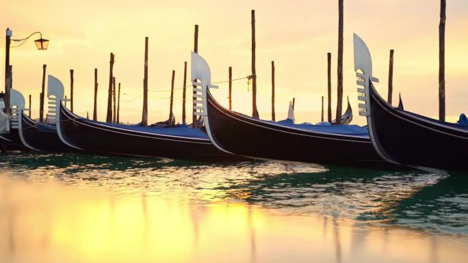 威尼斯的贡多拉船在金色的晨光中映照在石头岸边