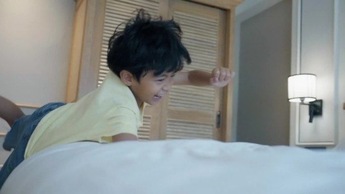 亚洲男孩和家人在旅游期间跳上酒店的床。