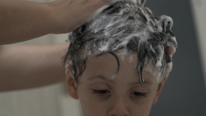 在超级慢动作中给孩子洗头，在超级慢动作800 FPS中，小男孩洗澡时的头部特写