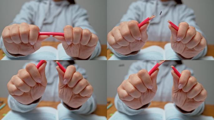 女人的手在掰一支红色的铅笔