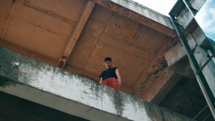 一个亚洲人站在建筑物的混凝土边缘从高处往下看