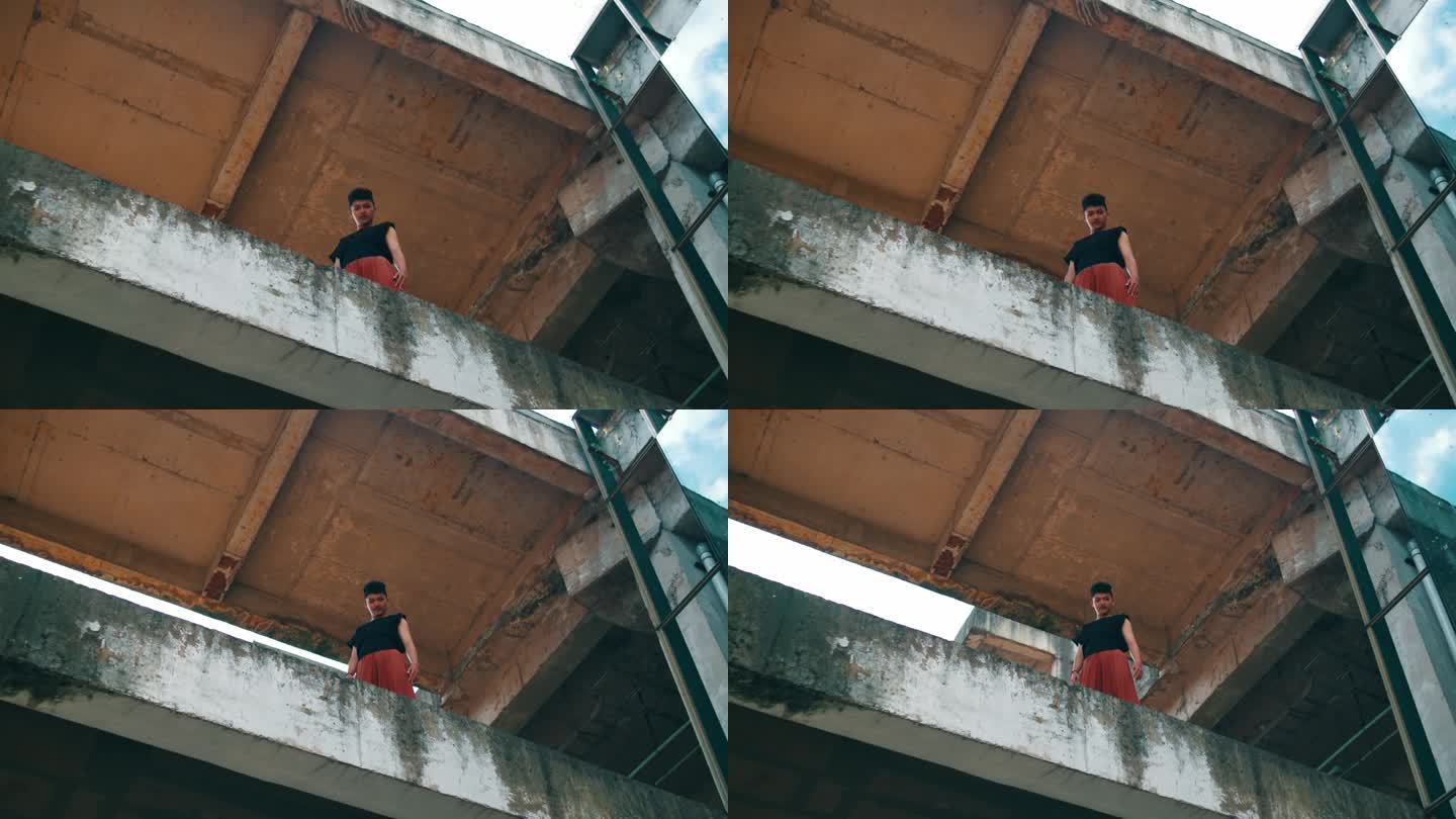 一个亚洲人站在建筑物的混凝土边缘从高处往下看