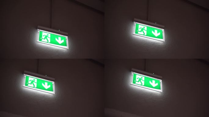墙上有照明的紧急出口标志，发生危险时指示正确逃生方向的向下箭头和奔跑人员，紧急出口标志，疏散方向