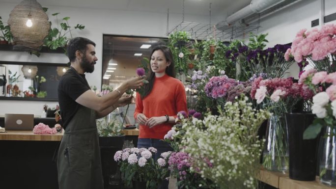 一位高兴的客户从小型商业花店买了一束花